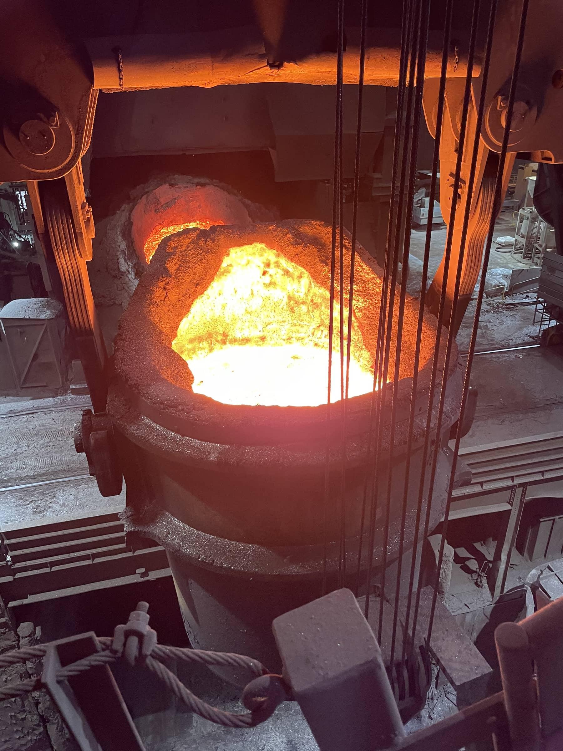 Glowing steel ladle hanging from a crane hook