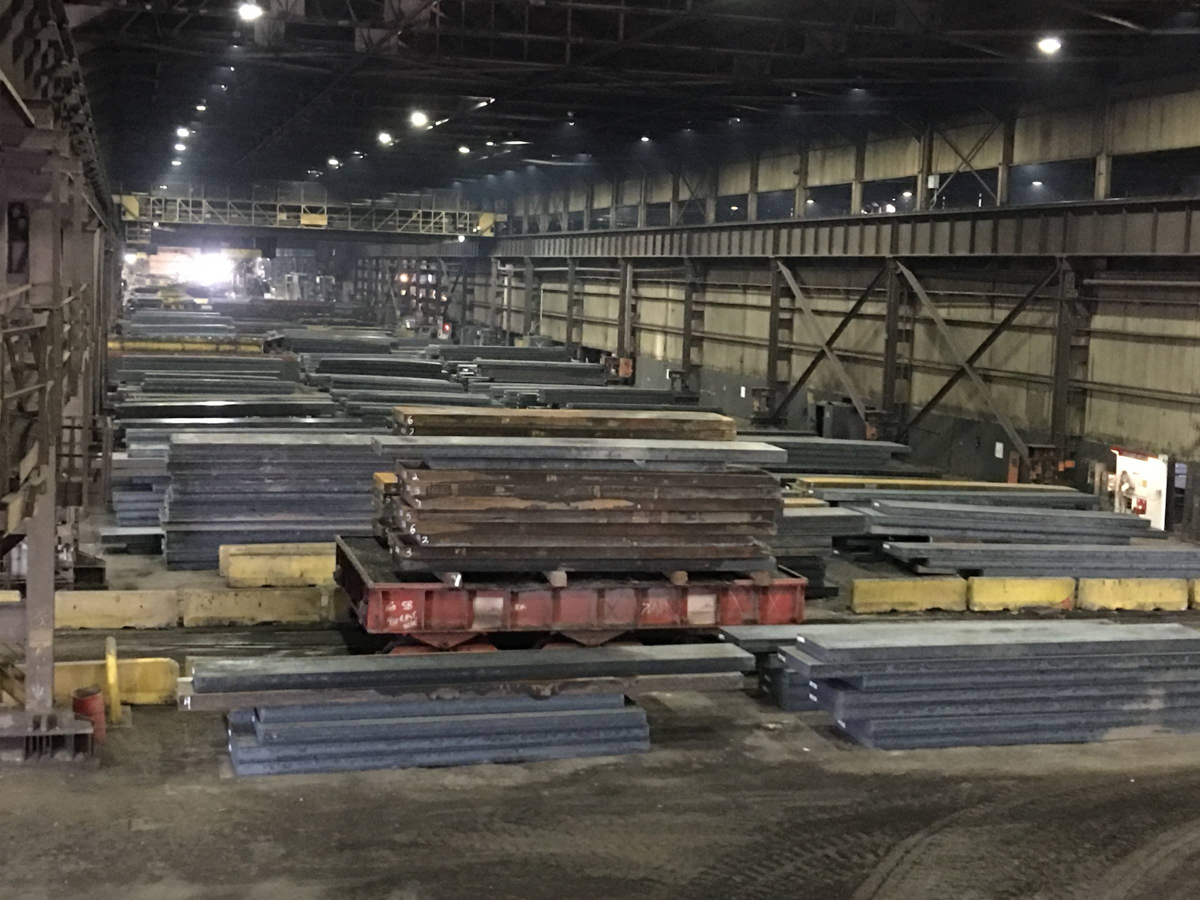 Stacked steel slabs in a dim storage bay